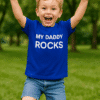 1. Gyermek játszik parkban, kék pólóban "My Daddy Rocks" felirattal.