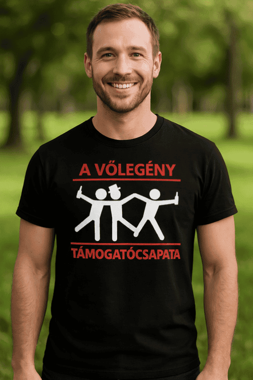 Háttér nélküli férfi fekete pólón, támogatócsoport felirattal, természetes park háttér, fiatal felnőtt, jókedvű arc.