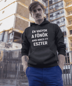 Egy férfi fekete kapucnis pulóverben, városi környezetben, modern épületek láthatók hátsóban.