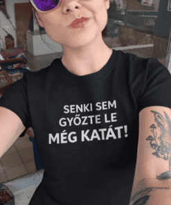 Mutatós nő napvédő lencsés szemüvegben és szlogent viselő pólóban, modern városi környezetben.