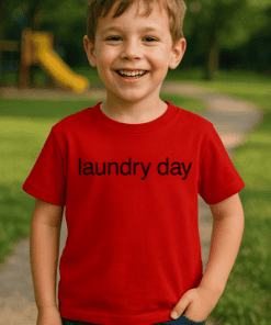 Mosolyogó kisfiú a parkban, piros pólóban, amelyen "laundry day" felirat látható.