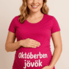 Biztonságos szülés várására készülő kismama, boldogan mosolyogva, magán viseli a "Októberben jövök".