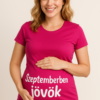 Sajátos, boldog nő a pink pólón, amelyen "Szeptemberben jövök" felirat látható.