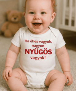 Mosolygó baba fehér pólóban, otthoni környezetben, játékok és plüssállatok a háttérben.