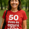 50 éves és egyre szebb feliratú női póló, természetes parkban, mosolygós arccal.
