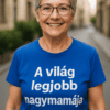 Idős nő mosolyogva utcán, kék pólón "A világ legjobb nagymamája" felirattal.