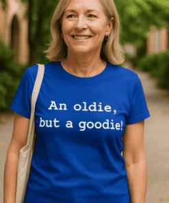 Nő mosolyogva, kék pólóval, "An oldie, but a goodie!" felirattal, parkban.