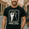 Fiatal férfi mosolyogva streeten, grafikus pólóval, "Game Over" felirattal.