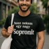 Fiatal férfi mosolyog, utcán, fekete sapkában és pólóban, Sopron felirattal.
