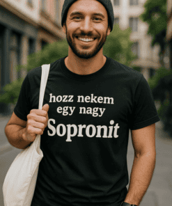 Fiatal férfi mosolyog, utcán, fekete sapkában és pólóban, Sopron felirattal.