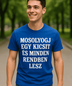 Férfi mosolyog, kék pólóval, parkban, természetes fényben, szöveg a pólón.